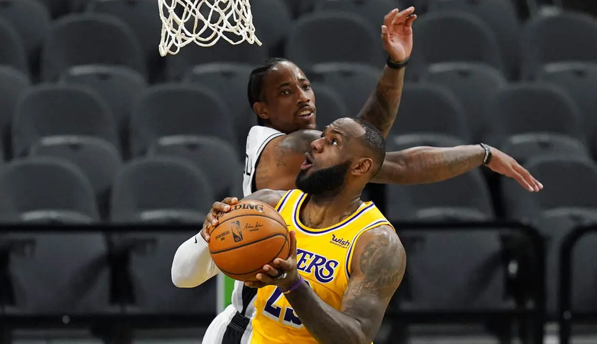 Pebasket Los Angeles Lakers, LeBron James, berebut bola dengan pebasket San Antonio Spurs, DeMar DeRozan, pada laga NBA di AT&T Center, Kamis (31/12/2020). LA Lakers menang dengan skor 121-107. (AP/Eric Gay)