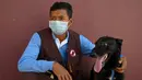Pelatih Khom Sokly duduk dengan seekor anjing yang dilatih untuk mendeteksi virus corona COVID-19 usai sesi pelatihan di Pusat Aksi Ranjau Kamboja, Provinsi Kampong Chhnang, Kamboja, 27 September 2021. Otoritas antiranjau darat Kamboja melatih anjing untuk mendeteksi COVID-19. (TANG CHHIN SOTHY/AFP)