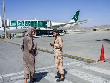 Anggota Taliban berpatroli di dekat pesawat Pakistan International Airlines (PIA) di bandara di Kabul, Senin (13/9/2021). Pesawat itu tercatat sebagai penerbangan komersial internasional pertama yang mendarat sejak Taliban merebut kembali kekuasaan di Afghanistan pada Agustus lalu (Bulent KILIC/AFP)