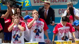 Joey Chestnut dan peserta lainnya saat bersaing mengikuti Kontes Makan Internasional Nathan, di New York, AS (4/7). Kategori wanita dimenangkan Miki Sudo yang menghabiskan 41 hot dog dalam sepuluh menit. (AP Photo/Bebeto Matthews)