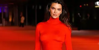 Ia memadukannya dengan korset pita diikat rapi di bagian samping. Serta rok panjangnya warna merah. [@kendalljenner]