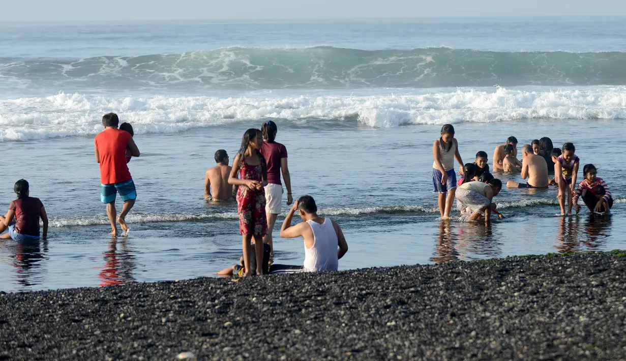 Sejumlah warga menjalani prosesi menyucikan diri saat Hari Banyu Pinaruh di pantai Keramas, Gianyar, Bali, Minggu (12/5/2019). Hari Banyu Pinaruh merupakan hari yang diyakini oleh umat Hindu sebagai waktu yang baik untuk menyucikan diri secara spritual dengan mandi di mata air  (SONNY TUMBELAKA/AFP)