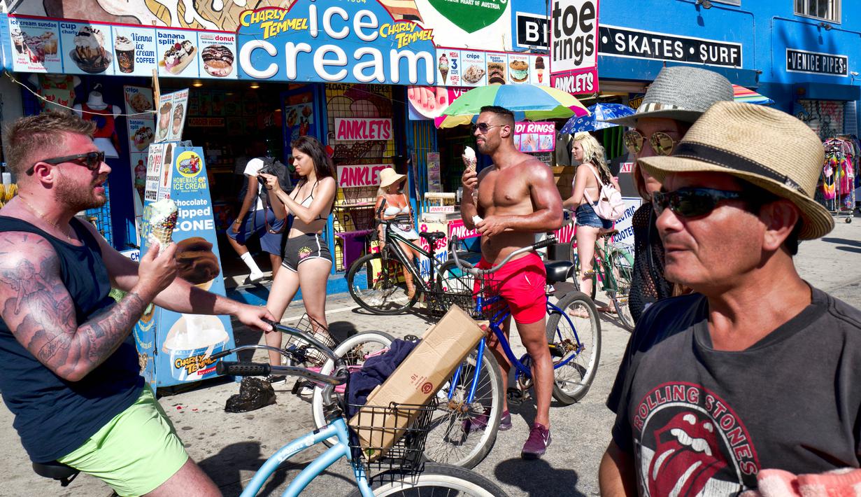 Para wisatawan makan es krim untuk mendinginkan diri dari panas ekstrem di Pantai Venice, Los Angeles, Amerika Serikat, Selasa (24/7). (AP Photo/Richard Vogel)