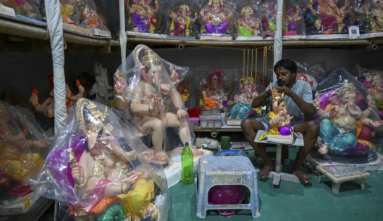 Perajin mengerjakan patung dewa Hindu berkepala gajah Lord Ganesha di sebuah lokakarya menjelang festival Ganesh Chaturthi di Mumbai (12/8/2021). Festival Ganesh Chaturthi adalah perayaan kelahiran Ganesha, dewa kebijaksanaan, kemakmuran, dan keberuntungan Hindu. (AFP/Punit Paranjpe)