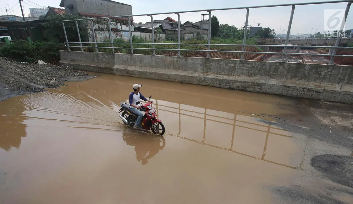 Pengendara motor melintasi genangan air di kawasan Kemiri Muka, Depok, Jawa Barat, Senin (2/10). Buruknya sistem drainase menyebabkan air selalu menggenang setiap musim hujan sehingga mengganggu aktivitas warga. (Liputan6.com/Immanuel Antonius)