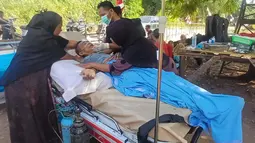 Seorang penyintas gempa menerima perawatan medis di luar puskesmas di Riung, provinsi Nusa Tenggara Timur, Indonesia, Sabtu, 15 Agustus 2026. (AP Photo/Ditho Wahyudin)