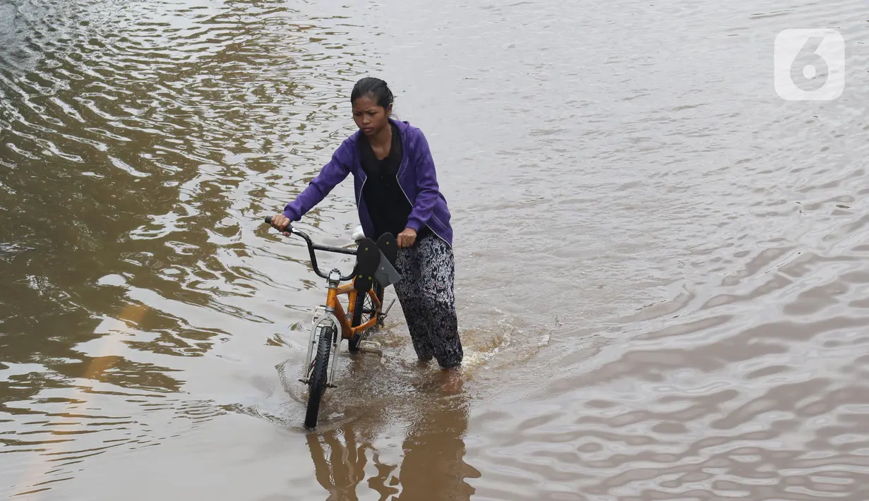 Warga membawa sepeda melewati perempatan Green Garden, Kedoya, Jakarta, Jumat (3/1/2020). Hingga hari ke-3, banjir masih menggenangi sekitar kawasan perempatan Green Garden, Kedoya akibatnya pengendara harus lebih waspada menghindari mesin kemasukan air. (Liputan6.com/Helmi Fithriansyah)