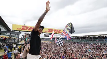 Pembalap Formula 1, Lewis Hamilton merayakan kemenangan bersama pengemarnya usai berlaga di Grand Prix Formula 1 Silverstone di Inggris, (5/7/2015). Hamilton berhasil finish di urutan pertama dengan waktu 1 jam 31 menit 27,729 detik. (Reuters/Hoch Zwei)