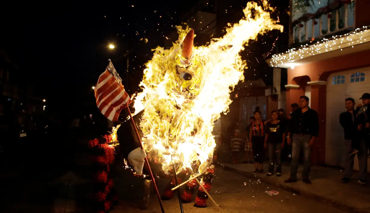  Sejumlah warga melihat pinata karakter Donald Trump yang dibakar saat perayaan tradisional, Pembakaran Iblis di Guatemala City, Guatemala (7/12). Perayaan Pembakaran Iblis ini digelar untuk mengusir roh-roh jahat. (Reuters/Luis Echeverria)