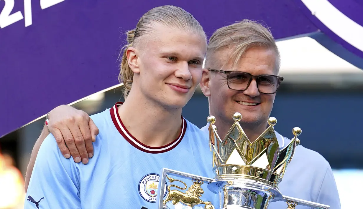 Striker Manchester City, Erling Haaland bersama sang ayah, Alf-Inge Haaland berpose dengan trofi Liga Inggris saat perayaan gelar usai laga pekan ke-37 menghadapi Chelsea di Etihad Stadium, Manchester (21/5/2023). Erling Haaland didatangkan pada awal musim 2022/2023 dari Borussia Dortmund. Bersama Manchester City ia menjelma menjadi monster menakutkan di depan gawang lawan. Sejauh ini ia telah mencetak 36 gol dan 7 assist dari 34 laga di Liga Inggris. (PA via AP Photo/Martin Rickett)