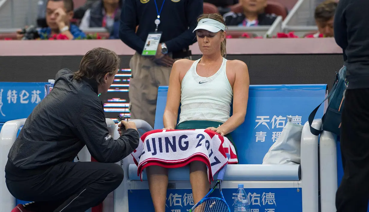 Maria Sharapova berbincang dengan pelatih saat istirahat selama pertandingan melawan Simona Halep dari Rumania pada  turnamen tenis China Terbuka di Diamond Court, Beijing (4/10). Sharapova kalah 6-2 6-2 dalam waktu 72 menit. (AFP Photo/Nicolas Asfouri)