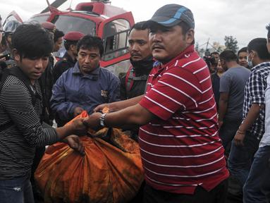 Petugas mengevakuasi korban tewas untuk dibawa ke rumah sakit, di sebelah utara Ibu Kota Nepal, Kathmandu, Senin (8/8). Tujuh orang, termasuk bayi dan pilot tewas akibat jatuhnya Helikopter Fishtail Air. (AFP PHOTO/BIKASH Karki)