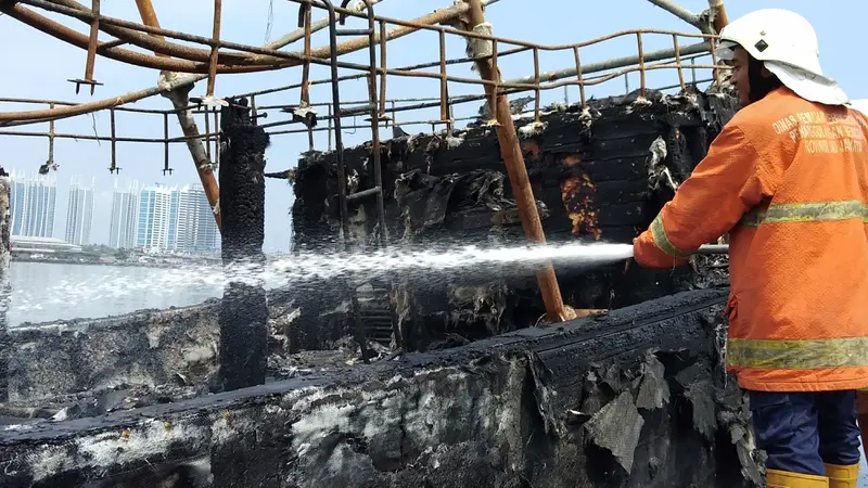 Petugas terus memadamkan kapal yang terbakar di Pelabuhan Muara Baru, Jakarta.