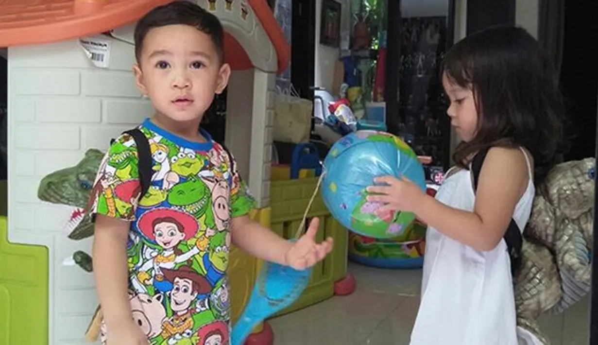 Seperti di foto ini, di mana keduanya terlihat sedang asik bermain. Rafathar dan Gempi sedang berdiri di pojok bermain mereka, dengan Rafathar yang memakai tas berbentuk dinosaurus serta Gempi memegang bola birunya. (Instagram/raffinagita1717)