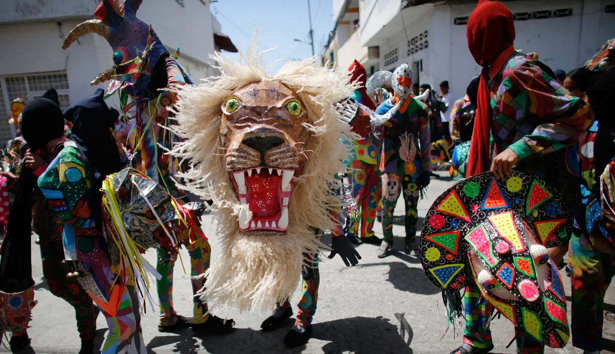 Sejumlah orang menari sambil mengenakan kostum dan topeng saat perayaan tradisional di Naiguata, Venezuela (31/5). Sejumlah orang kerasukan dan menari selama festival yang dikenal Dancing Devils ini di Naiguata. (AP/Arian Cubillos)
