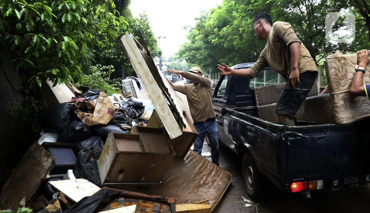 Petugas membuang barang milik warga di sepanjang jalan pascabanjir mulai surut di kawasan Kembangan, Jakarta Barat, Minggu (5/1/2020). Pasca banjir yang melanda hampir di kawasan Jakarta mulai surut, tumpukan sampah terlihat di sepanjang jalan dari rumah-rumah warga. (Liputan6.com/Johan Tallo)