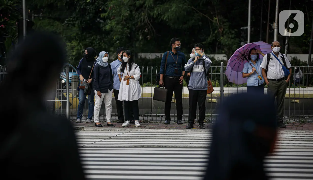 Sejumlah pekerja menunggu lampu merah pelican cross di kawasan Jalan Sudirman, Jakarta, Selasa (2/11/2021). Sektor non-esensial kini boleh mempekerjakan hingga 75 persen karyawannya dari kantor. Sebelumnya, angka ini dibatasi hingga 50 persen. (Liputan6.com/Faizal Fanani)