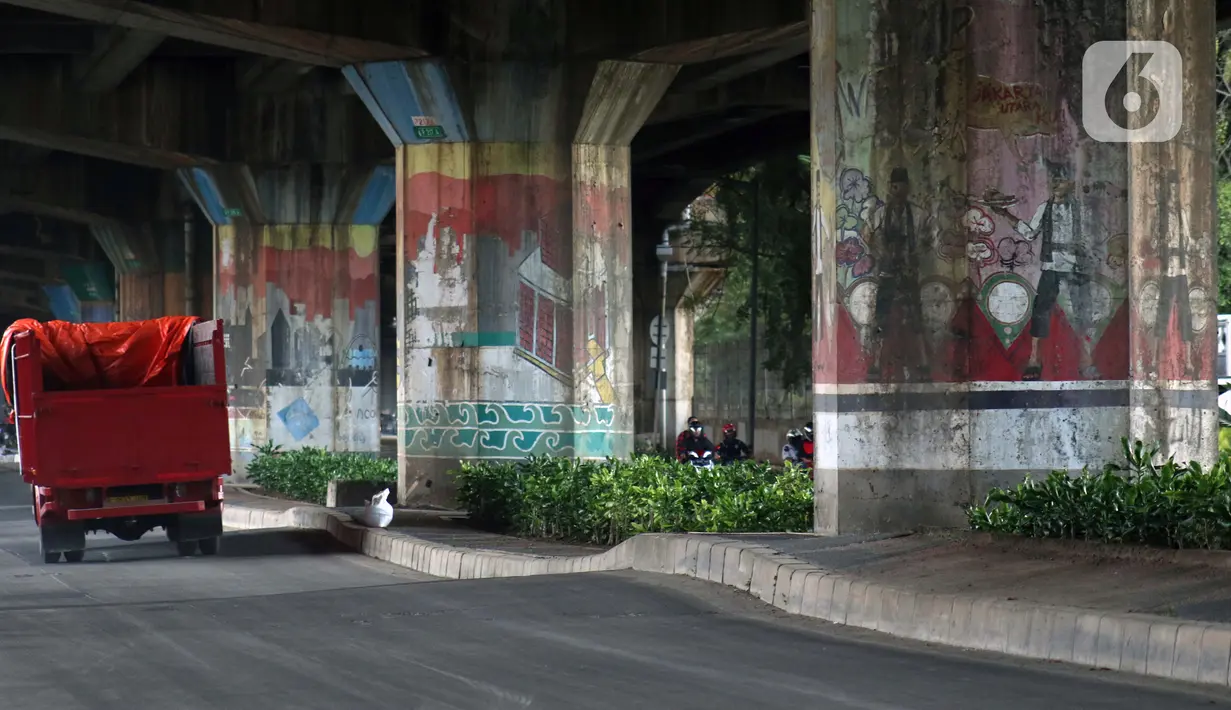 Pengendara truk melintasi sisi tiang penyangga Jalan Tol Pelabuhan Lingkar Dalam Jakarta di Jalan Ancol Timur, Jakarta, Selasa (16/6/2020). Seni mural yang dulu menghiasi tiang-tiang jalan tol di kawasan tersebut kini terlihat kusam dan berdebu. (Liputan6.com/Helmi Fithriansyah)