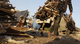 Seorang pria membawa tumpukan kayu di sebuah pasar di Sanaa, Yaman, pada 5 November 2020. Penduduk Yaman beralih menggunakan kayu untuk memasak karena kekurangan pasokan bahan bakar. (Xinhua/Mohammed Mohammed)