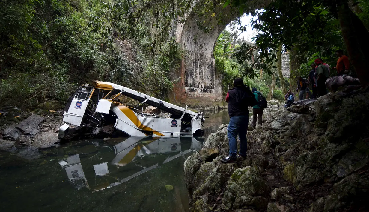 Awak media mengambil gambar sebuah bus berisi anggota tim sepak bola yang terjun ke jurang dari sebuah jembatan di Negara Bagian Veracruz, selatan Meksiko, Minggu (10/1). Sedikitnya 20 orang penumpang tewas dalam kecelakaan ini. (REUTERS/Yahir Ceballos)