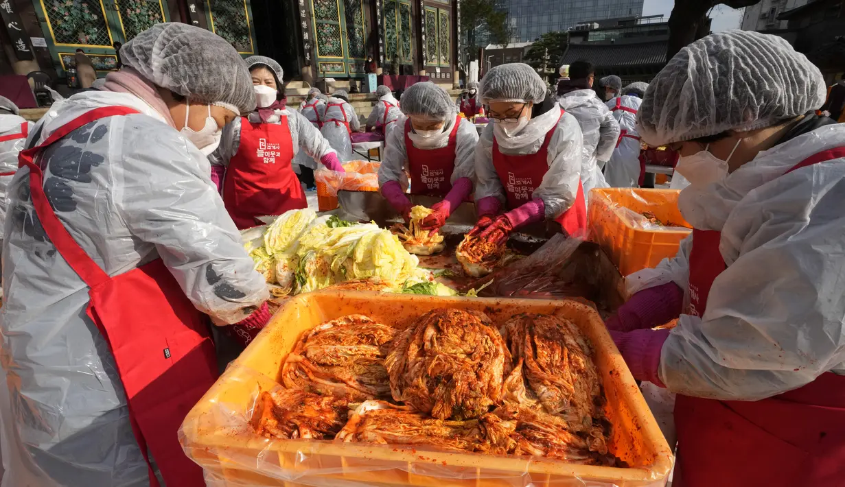 Relawan membuat kimchi untuk disumbangkan kepada tetangga yang membutuhkan, di sebuah kuil di Seoul, Korea Selatan, Kamis (2/12/2021). Sekitar 200 orang membuat 4.000 bungkus kimchi, dibuat dari fermentasi sayuran, seperti sawi putih, lobak, yang diberi bumbu pedas. (AP Photo/Ahn Young-joon)