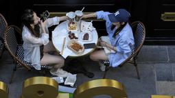 Seorang wanita bersulang dengan temannya di restoran yang dibuka kembali di sebuah pusat perbelanjaan di Beijing, Senin (6/6/2022). Pengunjung kembali ke restoran di sebagian besar Beijing untuk pertama kalinya dalam lebih dari sebulan sebagai pihak berwenang lebih lanjut melonggarkan pembatasan terkait pandemi wabah COVID-19. (AP Photo/Andy Wong)