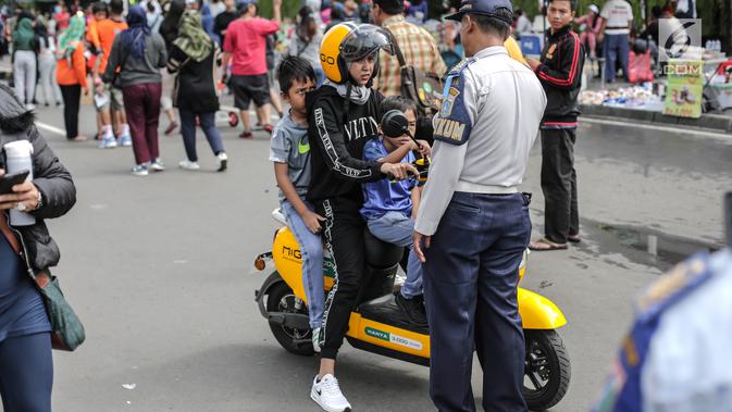 Petugas Dishub mensosialisasikan kepada pengendara sepeda motor listrik Migo saat melintasi CFD di Bundaran HI Jakarta, Minggu (17/2). Sosialisasi dilakukan karena tidak memenuhi teknis kendaraan bermotor di jalan raya. (Liputan6.com/Faizal Fanani)
