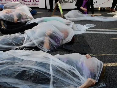 Para pengunjuk rasa membungkus diri dengan plastik saat melakukan aksi di Madrid, Spanyol (16/5). Mereka melakukan aksi yang disebut 'Platform 7N Against the Violence Against Women' untuk memerangi kekerasan terhadap perempuan. (AFP/Javier Soriano)