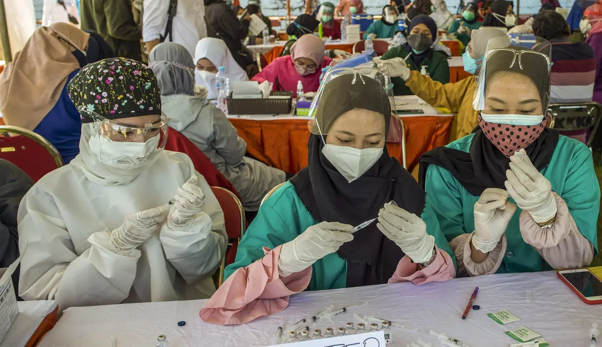 Dokter menyiapkan jarum suntik dan vaksin virus corona COVID-19 Sinovac di klinik vaksinasi massal darurat di lapangan sepak bola di Surabaya, Jawa Timur, Selasa (6/7/2021). Indonesia tengah memerangi gelombang infeksi baru yang belum pernah terjadi sebelumnya. (JUNI KRISWANTO/AFP)