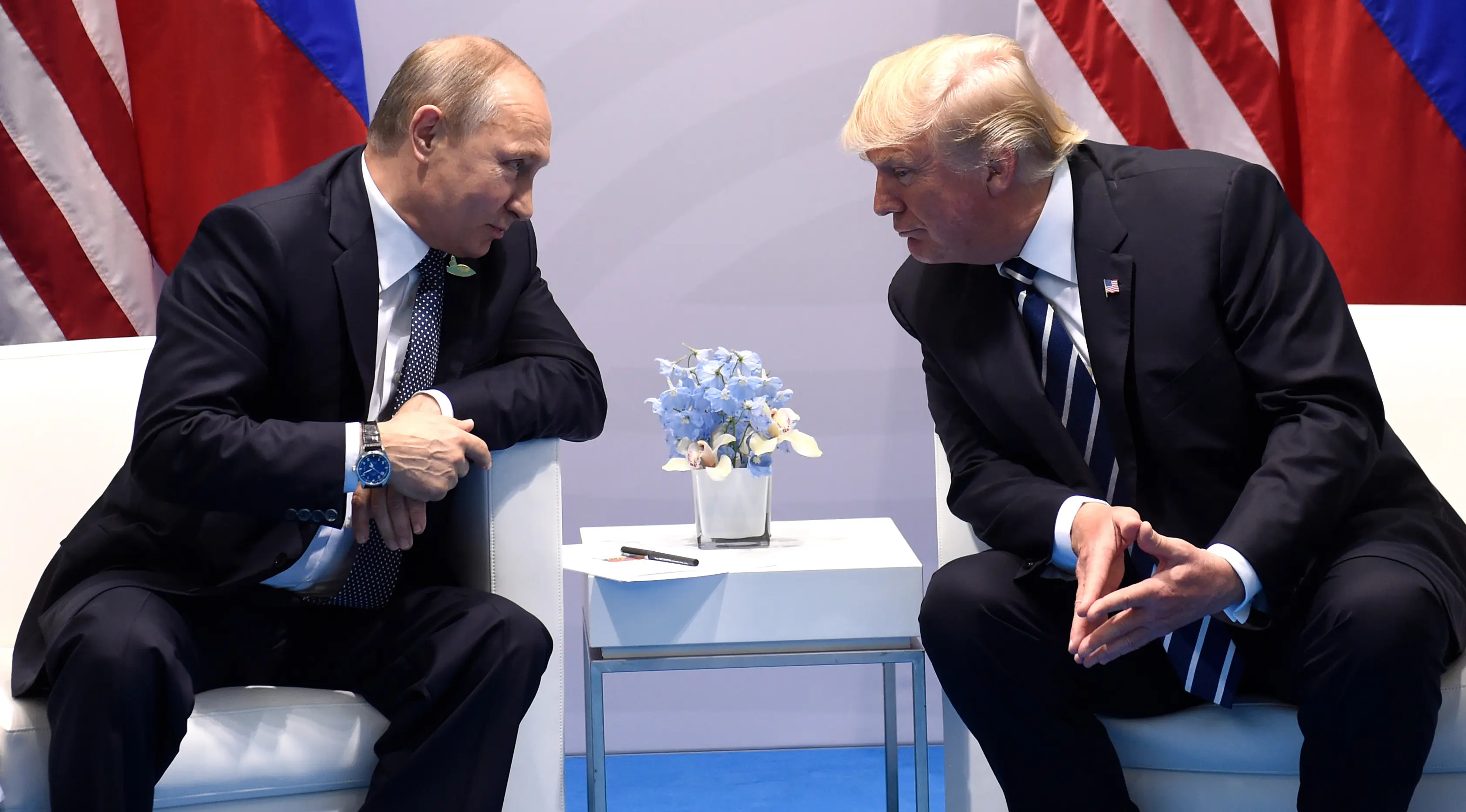 Presiden AS, Donald Trump (kanan) dan Presiden Rusia Vladimir Putin saling bertatapan saat bertemu di KTT G20, di Hamburg, Jerman (7/7). Keduanya dikabarkan ingin memperbaiki hubungan kedua negara.  (AFP Photo/Soul Loeb)