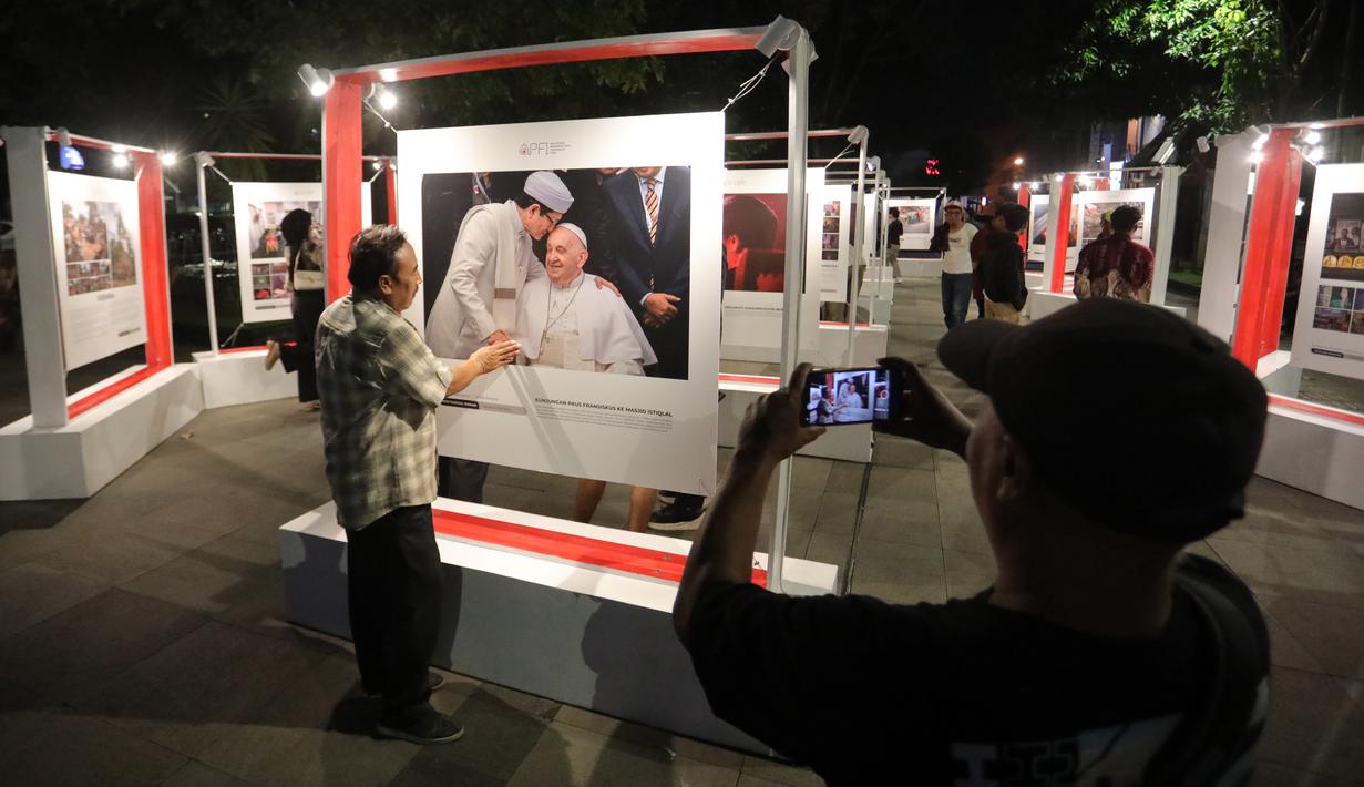 Pengunjung memperhatikan foto yang dipamerkan pameran foto para pemenang Anugerah Pewarta Foto Indonesia (APFI) 2025 di Loji Gandrung, Solo, Jawa Tengah, Jumat (25/4/2025). (merdeka.com/Arie Basuki)