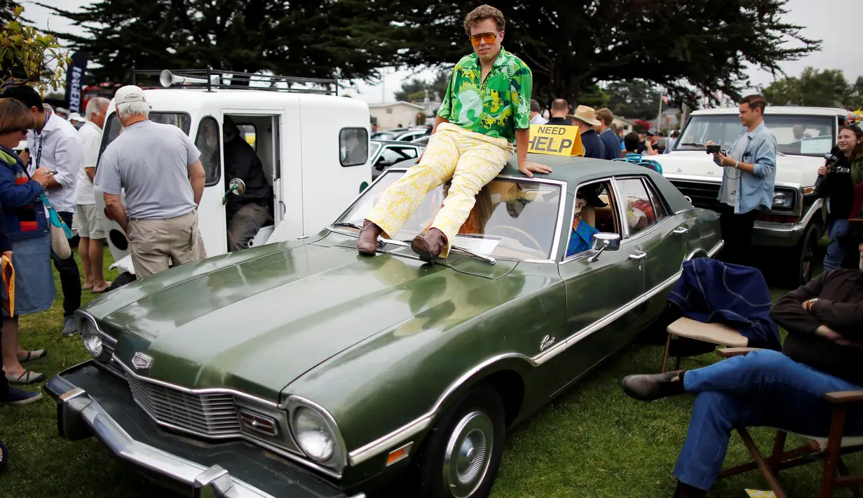 Seorang pengunjung duduk di atas mobil 1973 "Vomit Comet" selama Concours d'lemon di Seaside, California, AS, (20/8). Para pengunjung dibuat terpana dengan Mobil antik yang dipamerkan dan ingin memilikinya. (Reuters/Michael Fiala)