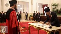 Presiden Jokowi menandatangani berita acara usai Wakil Ketua Mahkamah Konstitusi Anwar Usman menandatangani pengucapan sumpah sebagai Hakim Konstitusi di Istana Negara, Jakarta, Kamis (6/4). (Liputan6.com/Faizal Fanani)
