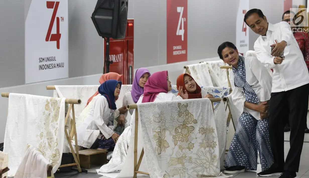 Presiden Joko Widodo dan Ibu Negara Iriana Jokowi  berselfie dengan sejumlah pembatik dalam acara batik kemerdekaan di Stasiun MRT Bundaran HI, Kamis (1/8/2019). Dalam kesempatan tersebut Jokowi berharap batik bisa dikembangkan sebagai sebuah brand. (Liputan6 com/Angga Yuniar)