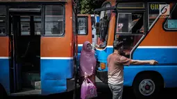 Seorang wanita melintas diantara Metromini di Terminal Blok M, Jakarta, Rabu (26/7). Menurut pihak Dishub DKI, revitalisasi tersebut melibatkan langsung para pemilik kendaraan Metromini. (Liputan6.com/Faizal Fanani)