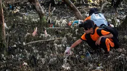 Seorang anak membersihkan sampah pada kegiatan World Cleanup Day 2019  di kawasan pantai di Surabaya, Sabtu (21/9/2019). Aksi bersih-bersih sampah yang digelar secara serentak di 157 negara ini mengajak masyarakat untuk bijak menggunakan plastik.  (JUNI KRISWANTO / AFP)