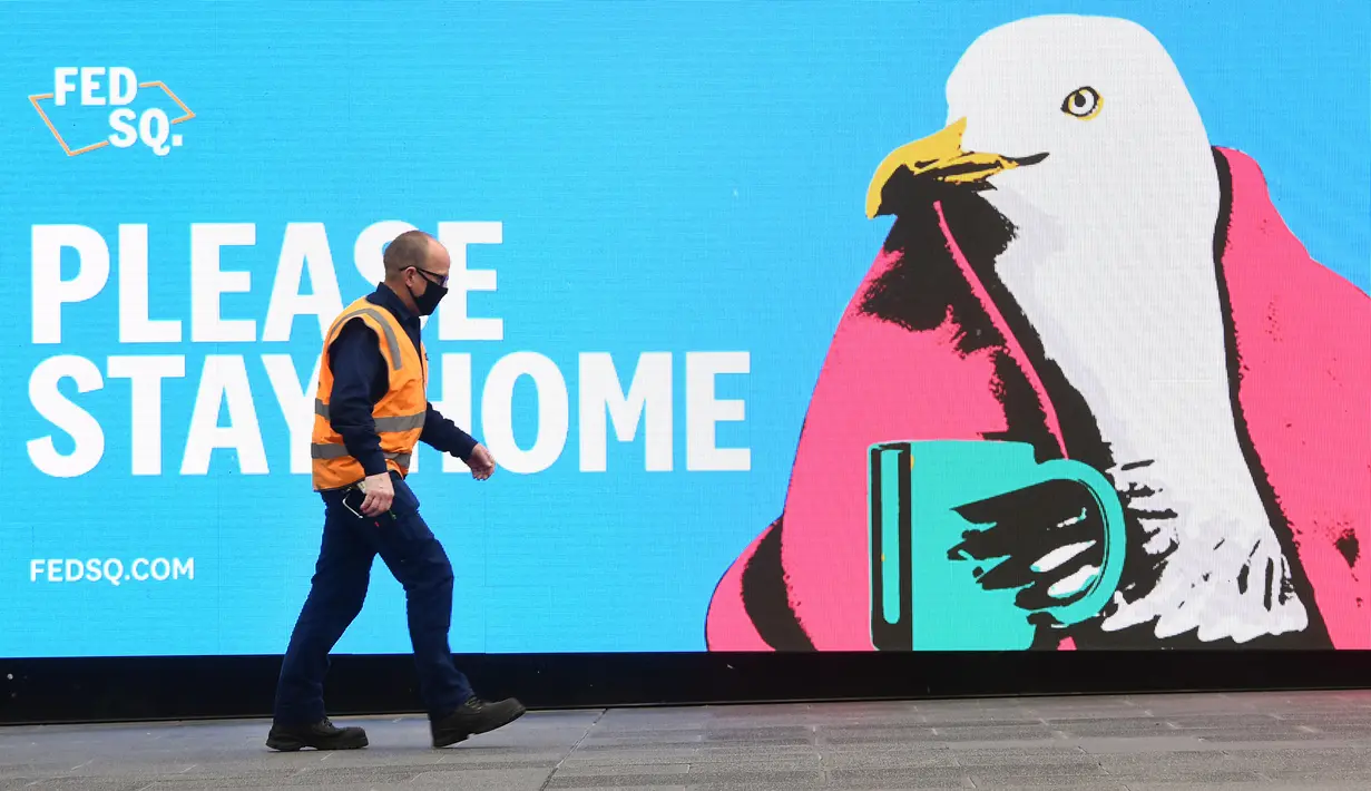 Seorang pria melewati tanda yang mendorong orang untuk tinggal di rumah saat pemberlakukan lockdown di Melbourne, Jumat (28/5/2021). Melbourne kembali menerapkan lockdown untuk keempat kalinya setelah wabah COVID-19 menyebar cepat di wilayah tersebut. (William WEST / AFP)