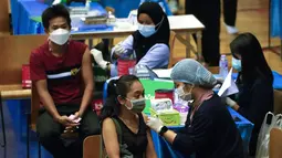 Petugas memberikan vaksin COVID-19 AstraZeneca kepada seorang perempuan di Bangkok, Thailand, 23 Februari 2022. Mulai 1 Maret, turis asing yang telah divaksin penuh hanya diminta menjalani satu kali tes PCR setelah kedatangan dan tes antigen mandiri setelah lima hari. (AP Photo/Sakchai Lalit)