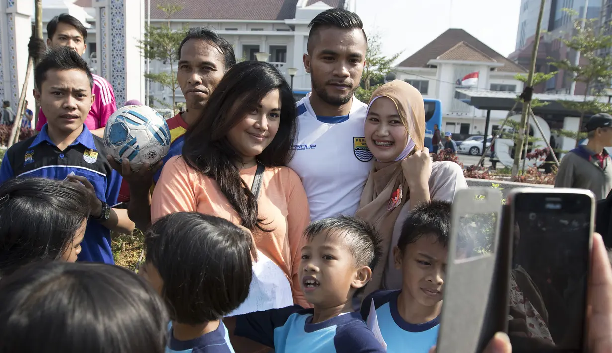 Pemain Persib, Zulham Zamrun menuruti permintaan warga yang meminta foto bersama usai latihan di Alun-alun Kota Bandung, Jawa Barat, Kamis (10/9/2015). (Bola.com/Vitalis Yogi Trisna)