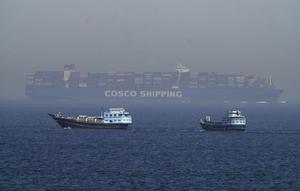 Dua perahu tradisional berlayar melewati sebuah kapal kontainer besar di Selat Hormuz, Jumat, 19 Mei 2023. (AP/Jon Gambrell)