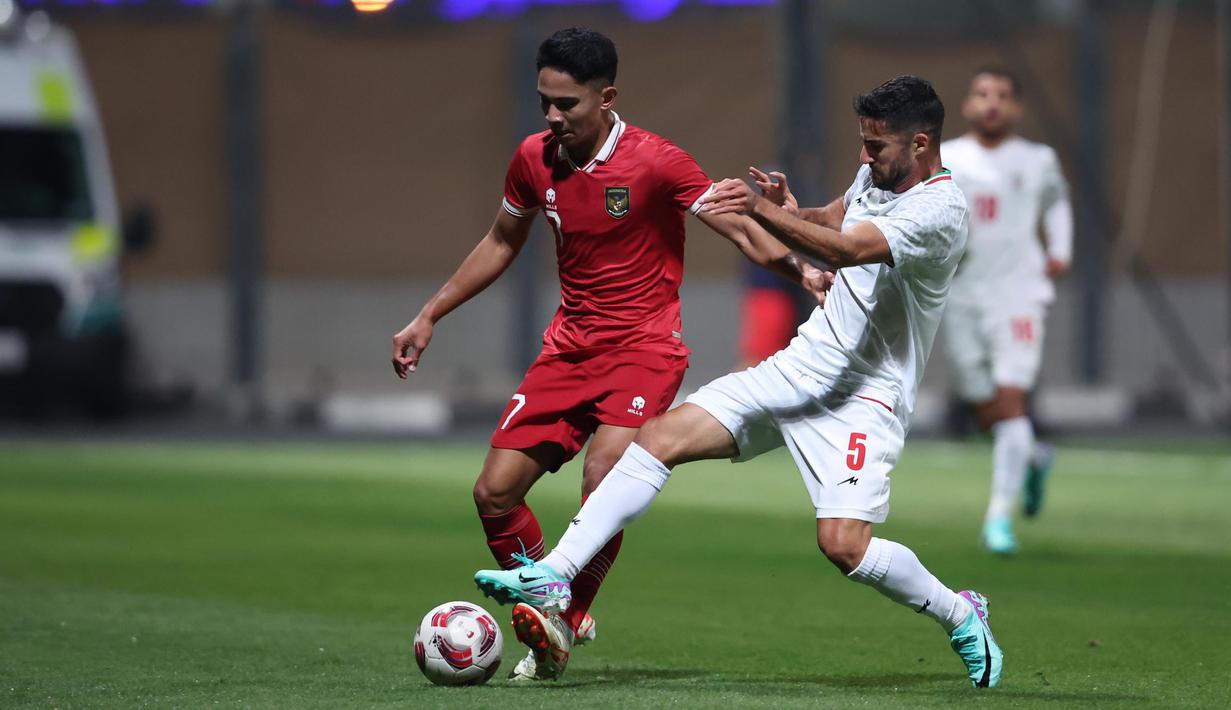 Gelandang Timnas Indonesia, Marselino Ferdinan (kiri) berebut bola dengan bek Timnas Iran, Milad Mohammadi pada laga uji coba terakhir menjelang Piala Asia 2023 di Al Rayyan Training Ground, Qatar, Selasa (9/1/2023) malam WIB. Timnas Indonesia kalah 0-5 dari Timnas Iran. (Dok. PSSI)