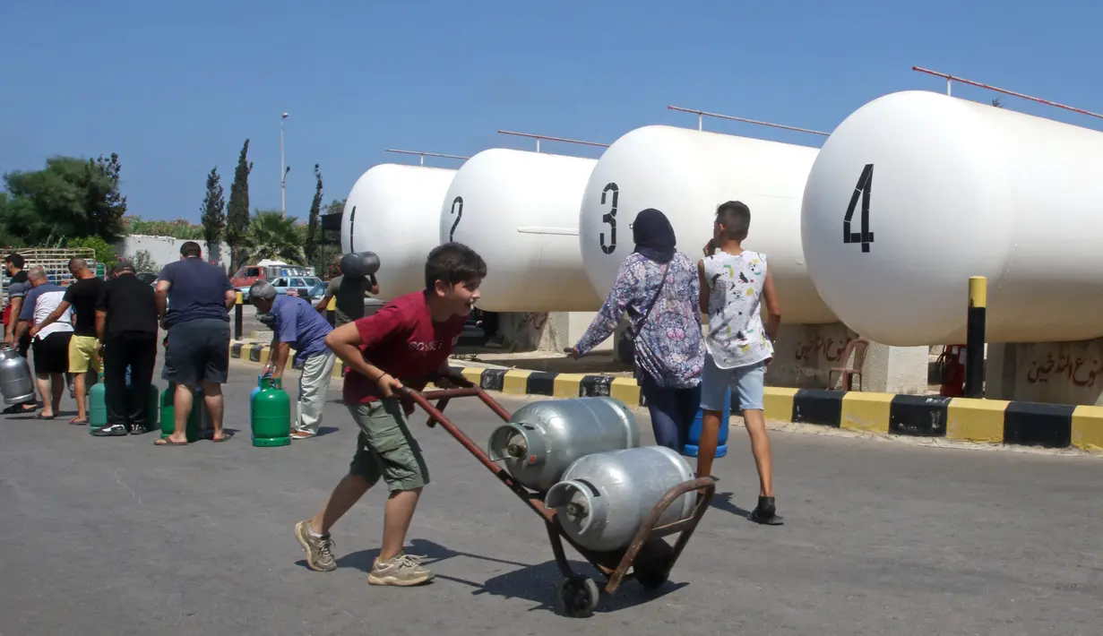 Seorang pria Lebanon membawa tabung gas di kota selatan Sidon, Selasa (10/8/2021). Warga Lebanon harus mengantre panjang demi membeli gas untuk memasak di tengah krisis ekonomi parah yang memicu kelangkaan berbagai kebutuhan pokok dari obat-obatan hingga bahan bakar. (Mahmoud ZAYYAT/AFP)