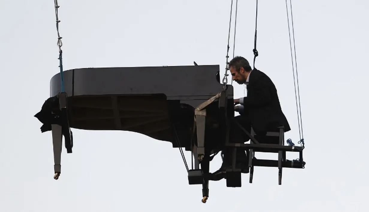 Aksi Pianis Ricardo de Castro Monteiro saat bermain piano sambil tergantung di udara selama Virada Cultural di Brasil (22/6/2015). Virada Cultural merupakan acara budaya 24 jam tanpa gangguan dengan berbagai cara unik.  (AFP PHOTO/Miguel Schincariol)