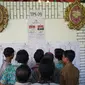 Warga melihat daftar nama caleg pada Pemilu 2019 di TPS 09 Kelurahan Sambirejo yang berkonsep pesta pernikahan di Semarang, Rabu (17/4). TPS itu dihiasi dengan dekorasi mewah dan menarik layaknya tempat pesta pernikahan agar semua warga senang ketika datang untuk mencoblos. (Liputan6.com/Gholib)