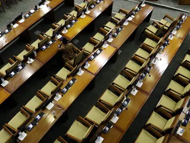 Seorang anggota DPR menghadiri rapat paripurna Masa Sidang I Periode 2019-2020 di antara bangku yang tak terisi di Kompleks Parlemen, Senayan, Jakarta, Kamis (22/8/2019). Rapat yang membahas RUU APBN Tahun 2020 beserta nota keuangannya itu hanya dihadiri 55 orang. (Liputan6.com/Johan Tallo)