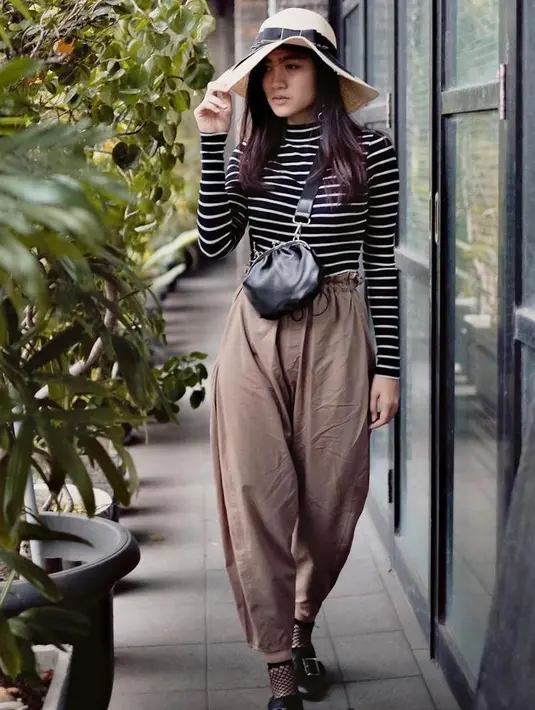 Outfit liburan lainnya yang bisa kamu jadikan inspirasi adalah gaya kasual ala Febby Rastanty berikut ini. Mix and match stripe long sleeve dengan wide leg pants dan floppy hats. (Instagram/febbyrastanty).