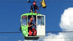 Penumpang dengan membawa anak kecil dikeluarkan dari kereta gantung saat proses evakuasi di Koln, Jerman, Minggu (30/7). 32 kereta gantung mendadak terhenti usai menabrak tiang penyangga hingga membuat penumpangnya terjebak. (Martin Oversohl/dpa via AP)