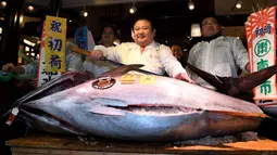 CEO Sushi Zanmai, Kiyoshi Kimura berpose dengan ikan tuna seberat 212 kg di depan restorannya, dekat pasar ikan Tsukiji, Tokyo, Kamis (5/1). Pada pelelangan pertama tahun 2017, ikan itu terjual 74,2 juta yen atau setara Rp 85 M. (TOSHIFUMI KITAMURA/AFP)