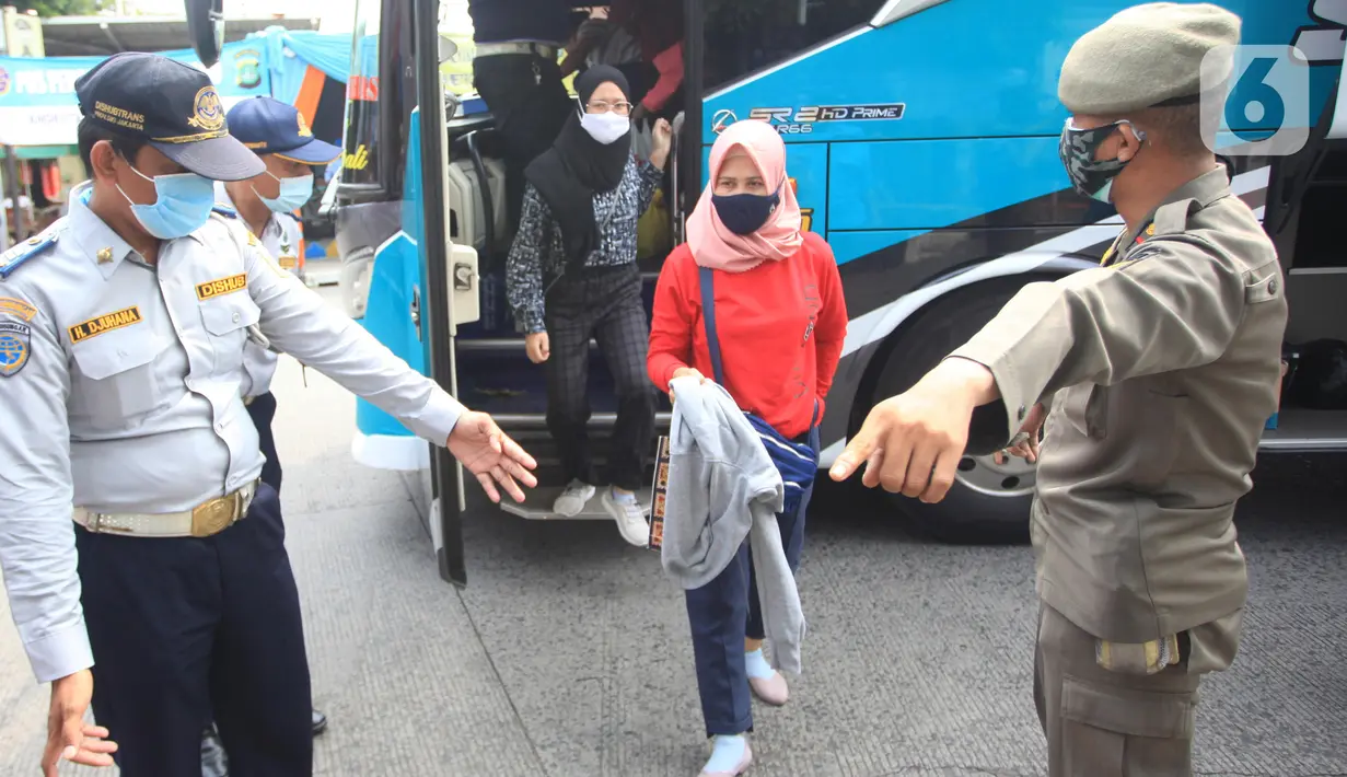 Petugas mengarahkan penumpang yang turun dari bus Antar Kota Antar Provinsi (AKAP) di Terminal bus Kalideres, Jakarta Barat, Senin (17/5/2021). Arus balik pemudik mulai terlihat di sejumlah terminal di Jakarta, salah satunya di Terminal Kalideres. (Liputan6.com/Angga Yuniar)