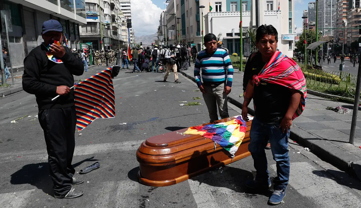 Peti mati berisi jenazah orang yang tewas dalam bentrokan antara pasukan keamanan dengan pendukung mantan Presiden Evo Morales tergeletak di tengah jalan setelah polisi meluncurkan gas air mata pada prosesi pemakaman besar-besaran di El Paz, Bolivia, Kamis (21/11/2019). (AP Photo/Juan Karita)